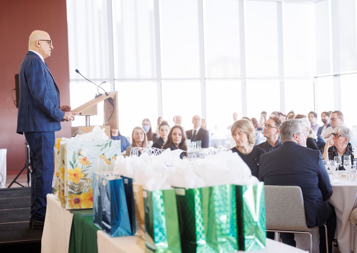 Dr. Haddad stands on stage speaking to a crowd seated at tables.