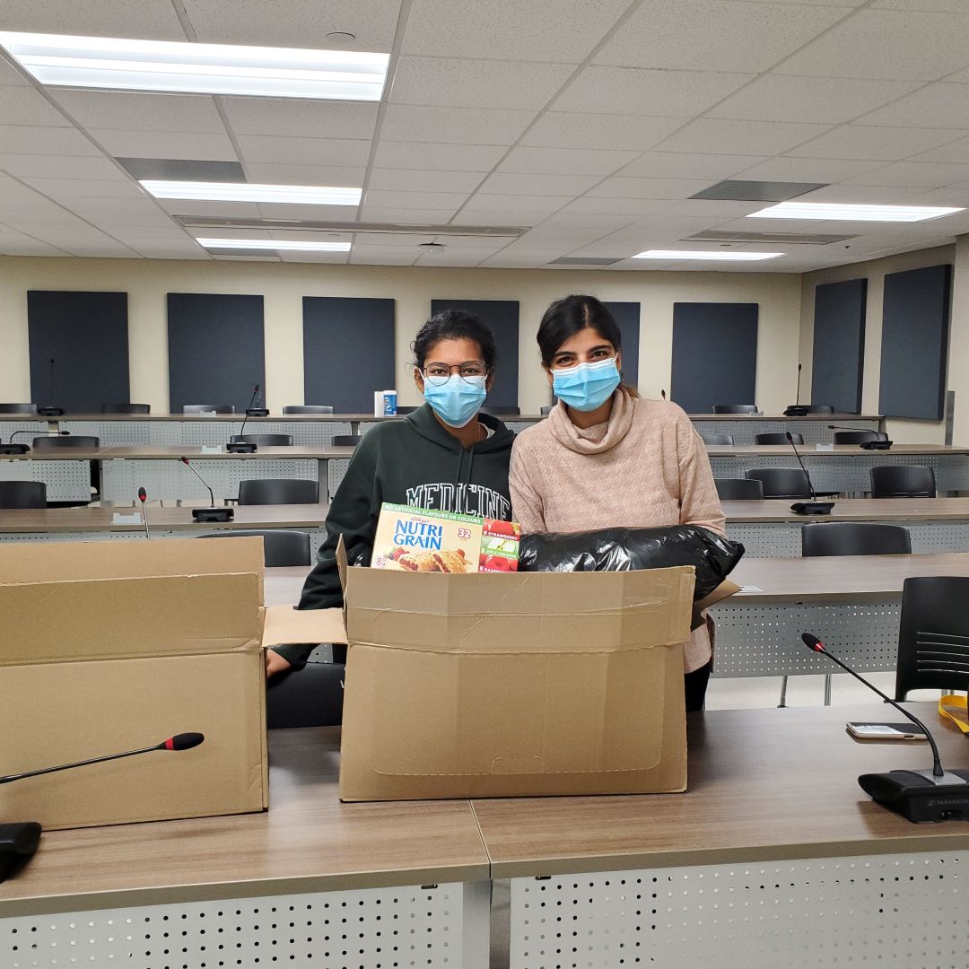 Medical students Kirti Garg, left, and Rubia Ahmed pack up donation items for the Winter Clothing Drive for OPG initiative. (Submitted photo)