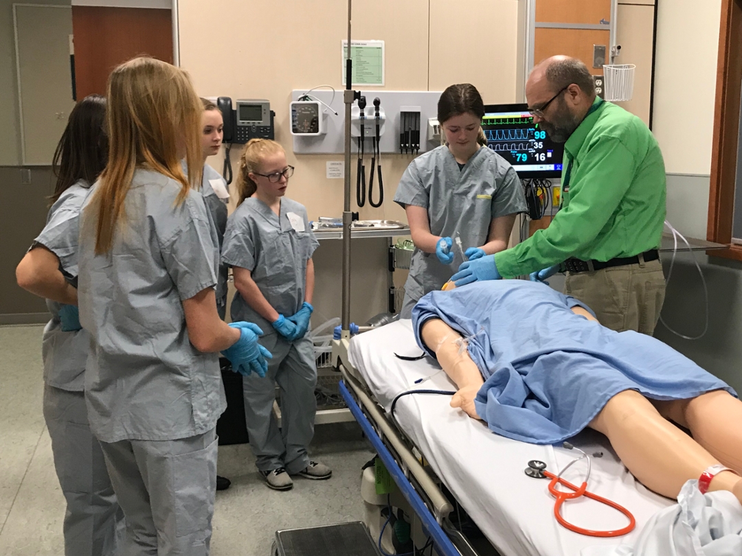 Simulation technician Roger deWeerd, right, shows students how to perform an endotracheal intubation. Photo by Kristen McEwen