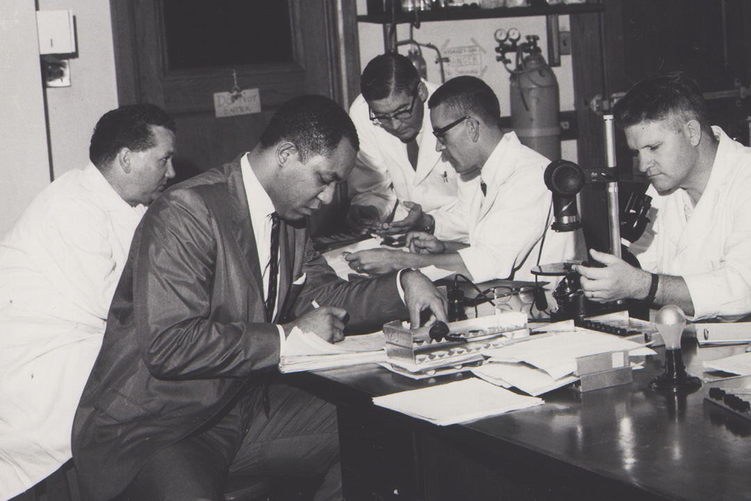 In 1963, PhD candidate Norman McDuffie (in suit), works with fellow researchers in the post-graduate tissue culture course, at the University of Saskatchewan. (Photo: University Archives A-3952)