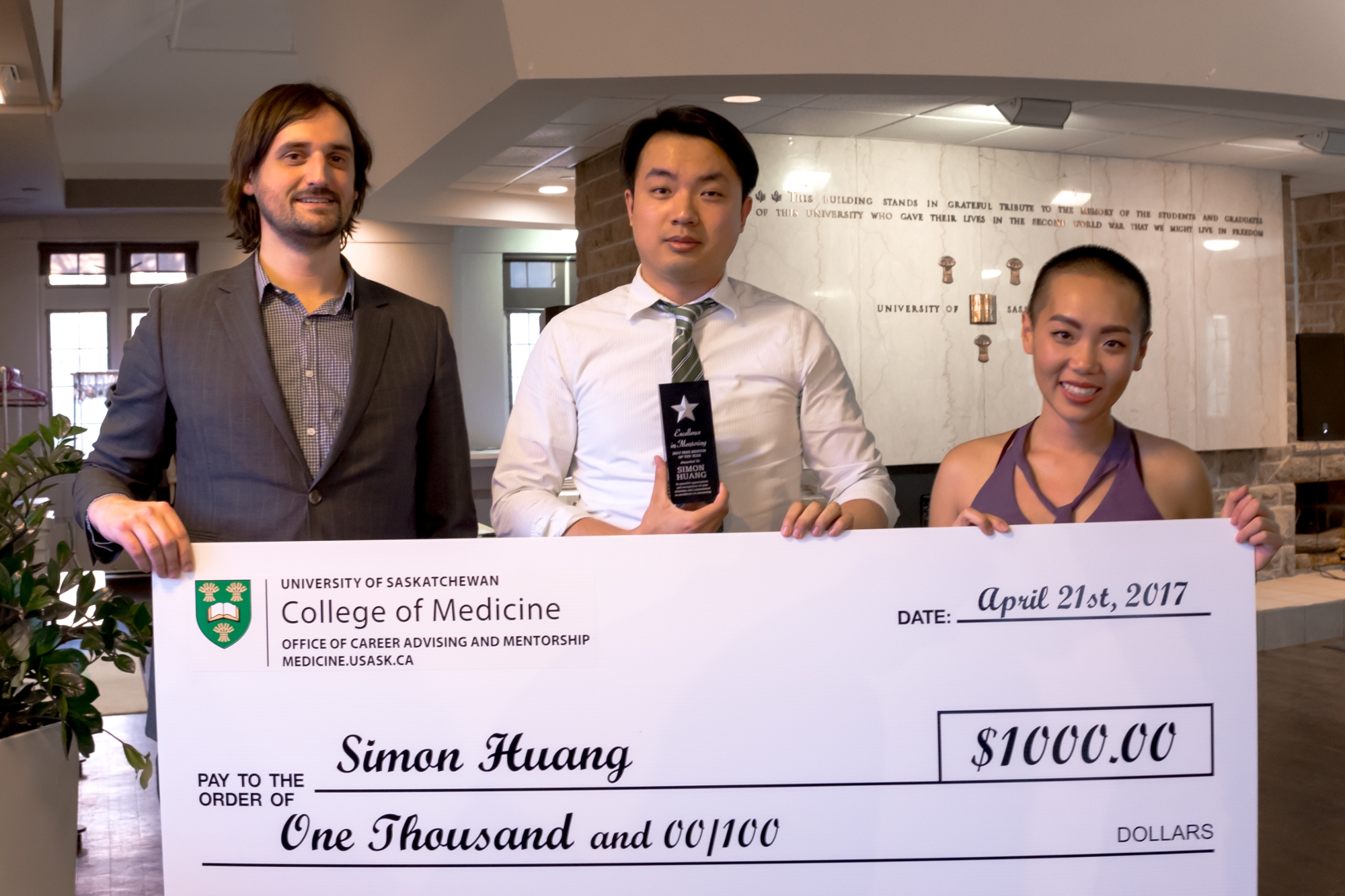 Dr. Brent Thoma, Simon Huang and Lily Xiao stand with Huang's novelty cheque. (Rob Nguyen, Class of 2019)